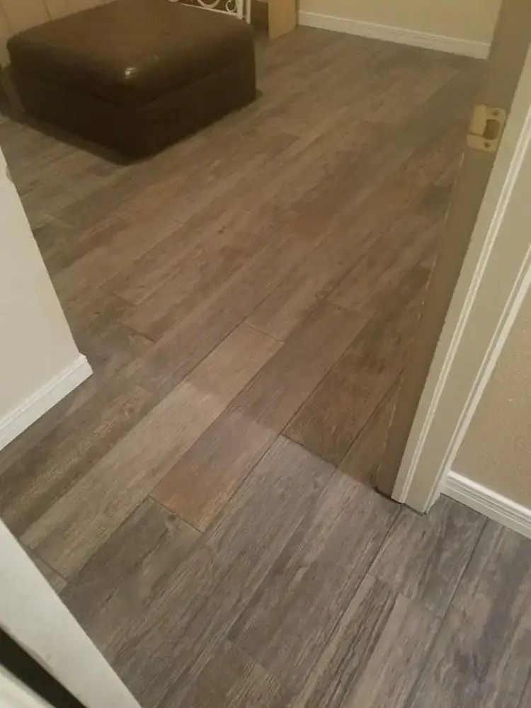 Empty hallway with wood-look flooring and a brown ottoman in the corner.