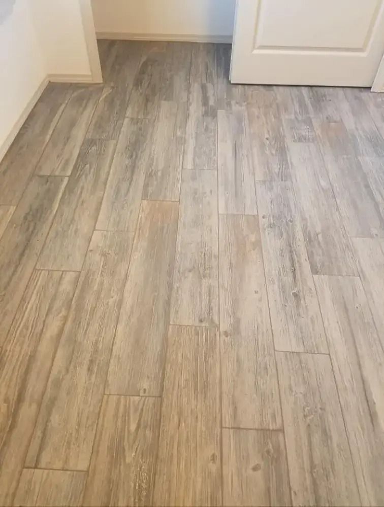 Light wood-look vinyl flooring in a room with beige walls and a white door.
