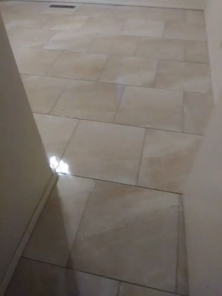 Tiled hallway floor with beige tiles and a bright light reflection near a doorway