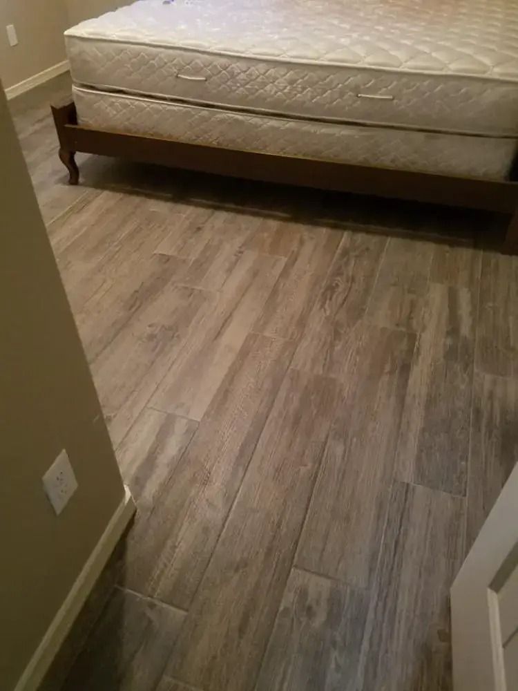 Bedroom with beige bed and wood-look flooring, viewed from the doorway.