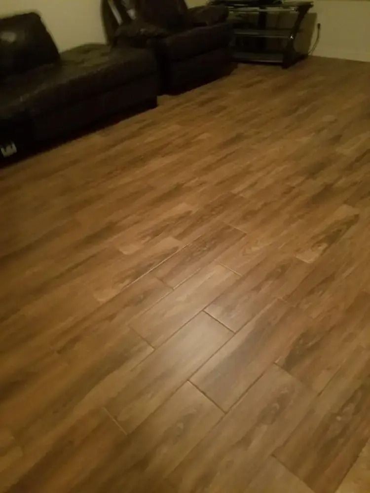 Empty living room with wood flooring and dark sofas along the wall