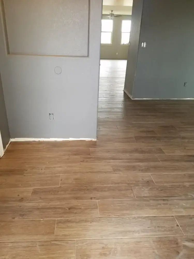 Empty room with gray walls and wood-look flooring, viewed toward a bright doorway.