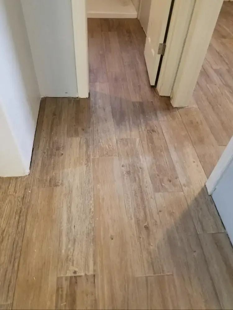 Narrow hallway with light wood flooring and white doorways.