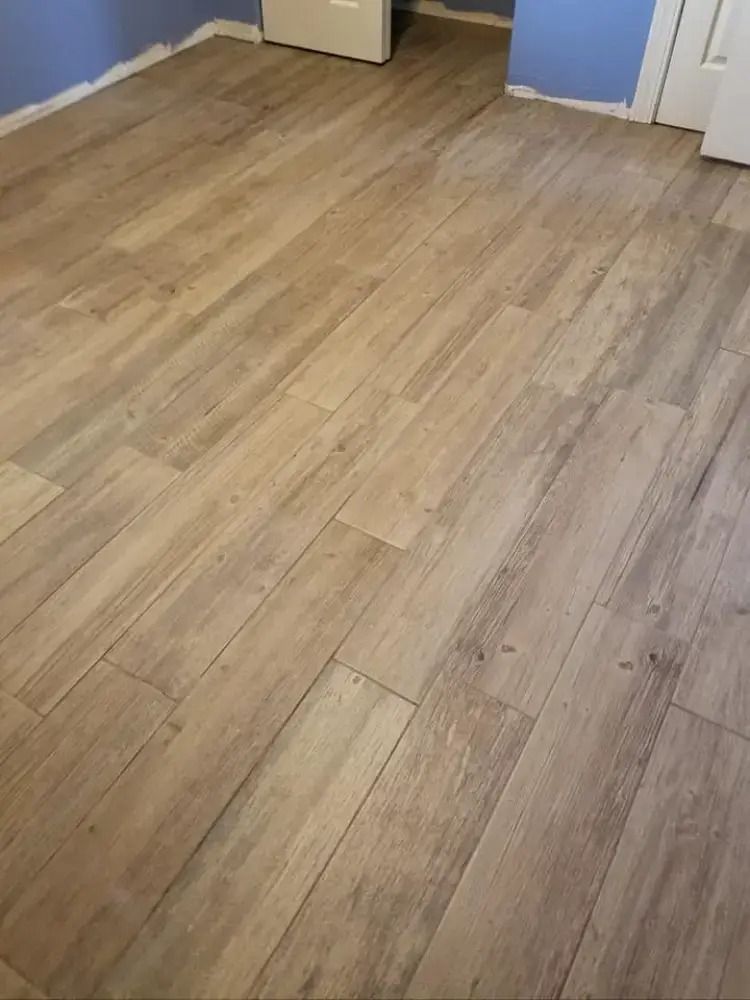 Empty room with light wood flooring and blue walls, viewed from a doorway.