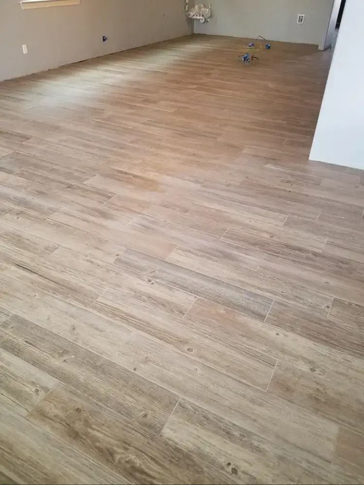 Empty room with light wood flooring and beige walls, viewed from a corner.