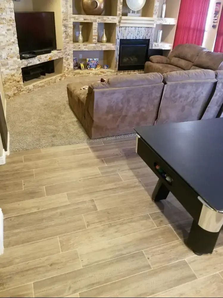 Living room with brown sofa, fireplace, TV, and black coffee table on wood flooring