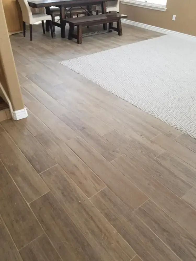 Living room with wood-look flooring, light carpet, and a small dining table by the window
