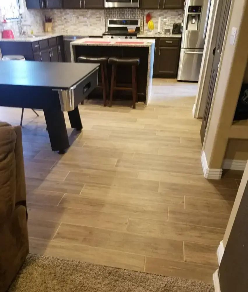 Open kitchen and dining area with light wood floors, a black table, and bar stools at a kitchen island.