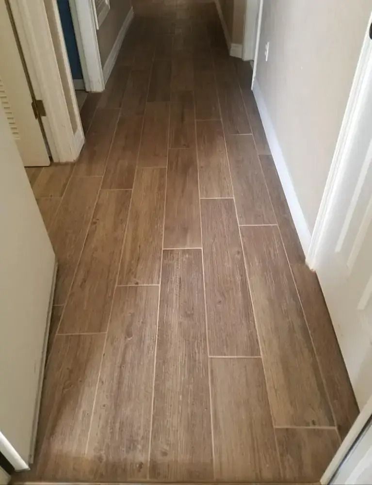 Narrow hallway with wood-look tile flooring and white walls/doors.