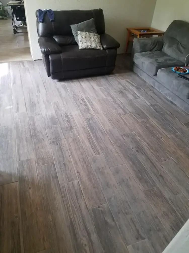 Living room with gray wood-look floor, black armchair, and gray sectional sofa