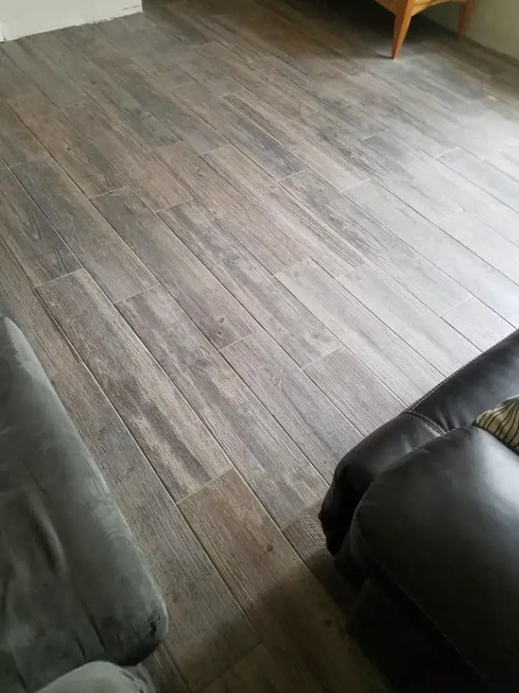 Gray wood-look floor between two dark chairs in a room