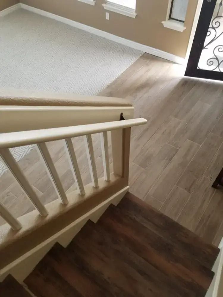 Staircase with white railing leading to a light wood floor entryway and carpeted landing near a front door.