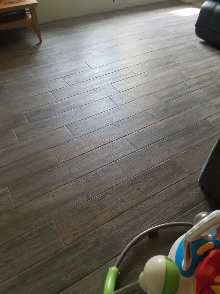 Dark wood plank floor in a living room, with part of a toy visible in the bottom right corner