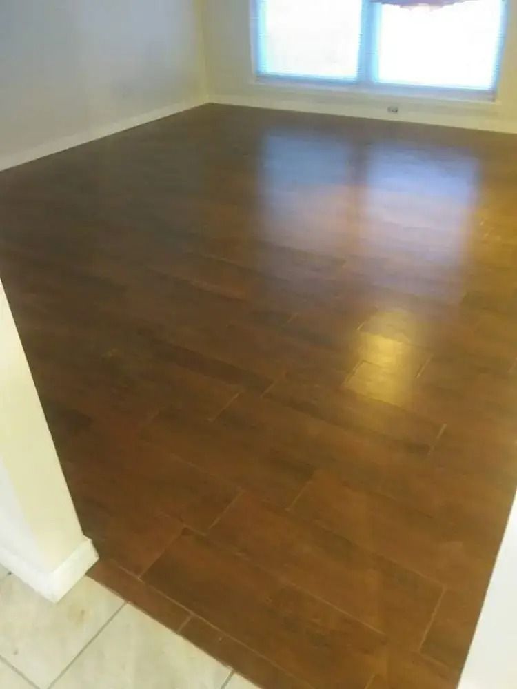 Empty room with dark wood floors, white walls, and a window letting in light