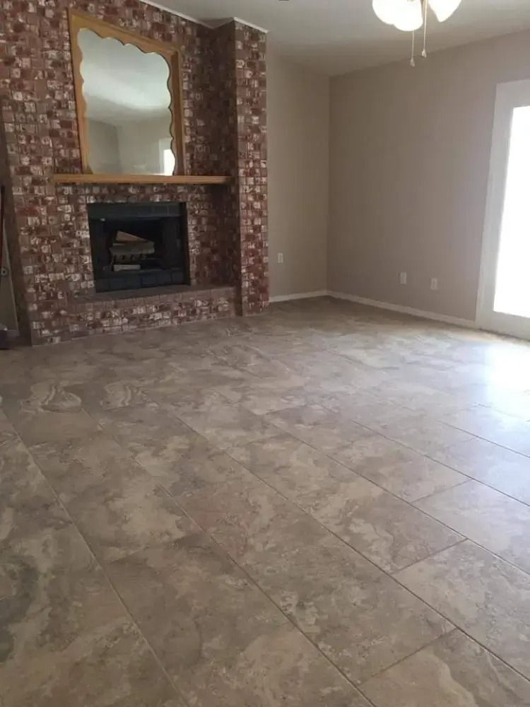 Empty living room with tiled floor, fireplace, and large window letting in light