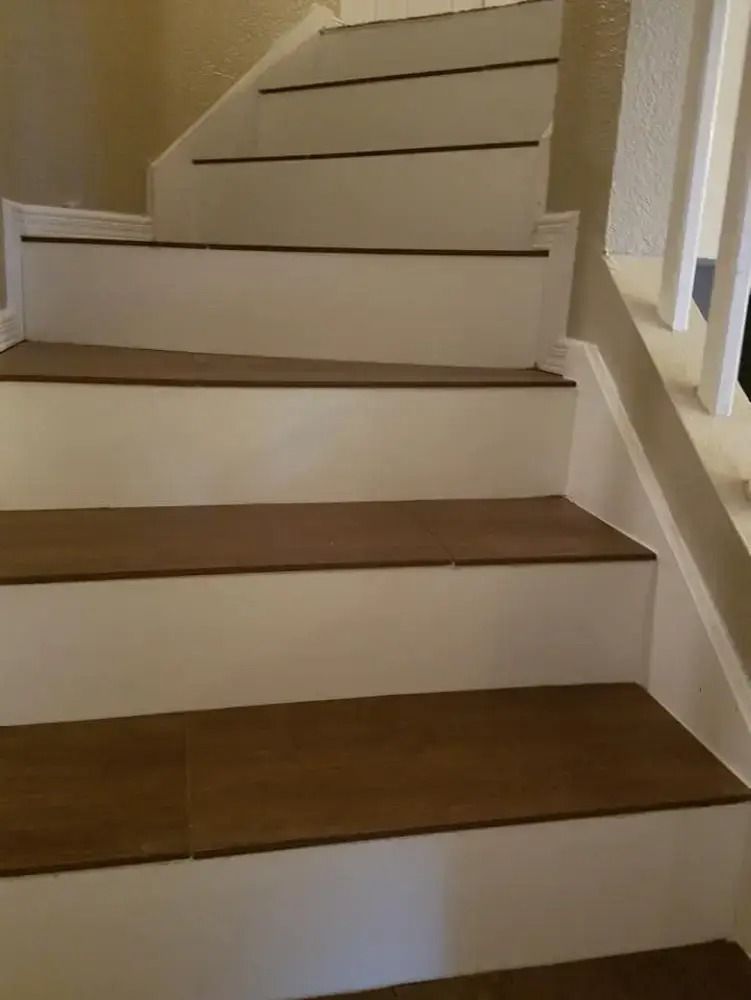 Indoor staircase with white risers, dark wood treads, and a beige wall and railing