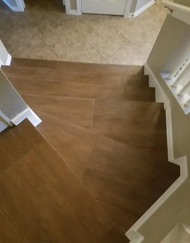 Staircase with brown wooden steps and white railings leading to a beige tiled landing
