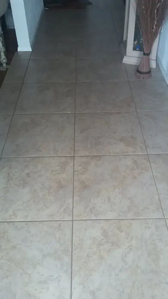 Indoor hallway with beige tiled floor leading into a dim room, flanked by walls and columns