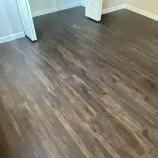 Empty room with dark wood-look flooring and white trim around doorways