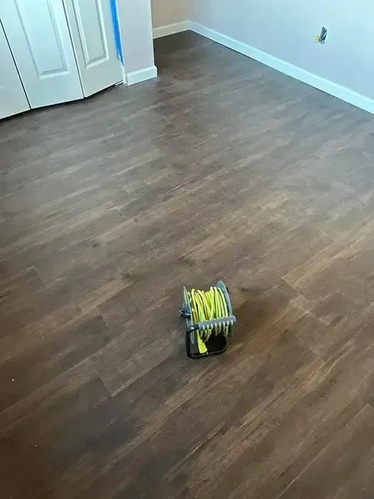 Small yellow-and-black tool on a wooden floor in an empty room.