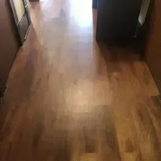 Wooden hallway floor with sunlight reflecting from a doorway ahead