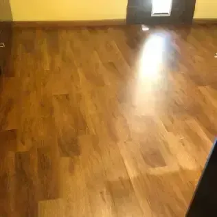 Wooden floor in an empty room, lit by a bright light near the back wall.