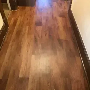 Narrow hallway with glossy wooden floor and beige walls, viewed from above.