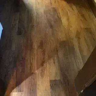 Close-up of a brown and tan wood floor with blurred objects at the edges