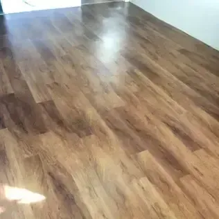 Shiny brown wooden floor in an empty room with bright light reflection