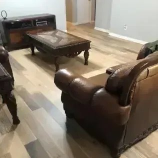 Living room with leather armchairs, coffee table, TV stand, and light wood flooring