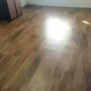 Wooden floor with a bright sunlit reflection and a cabinet in the corner.