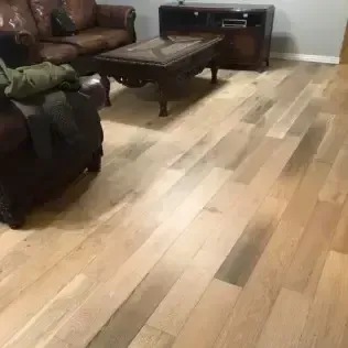 Living room with brown sofa, dark coffee table, and light wood flooring, plus a TV stand in the corner