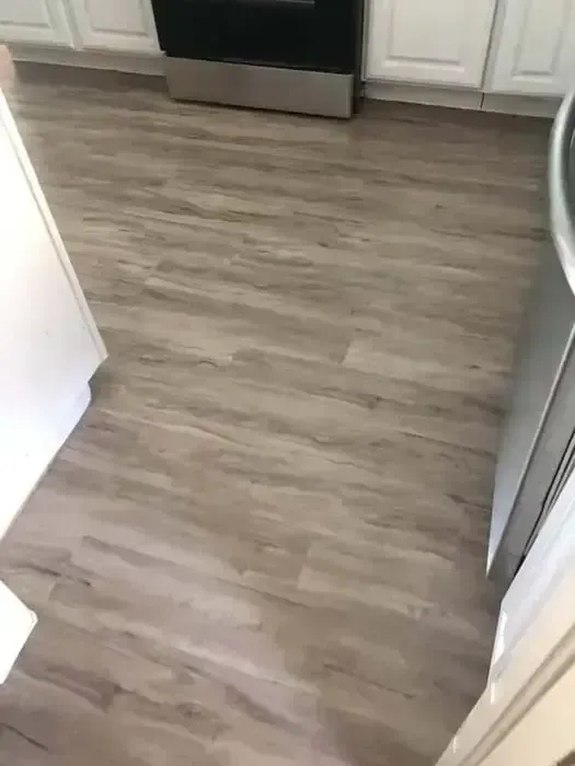 Empty kitchen with gray wood-look flooring and stainless steel appliances.