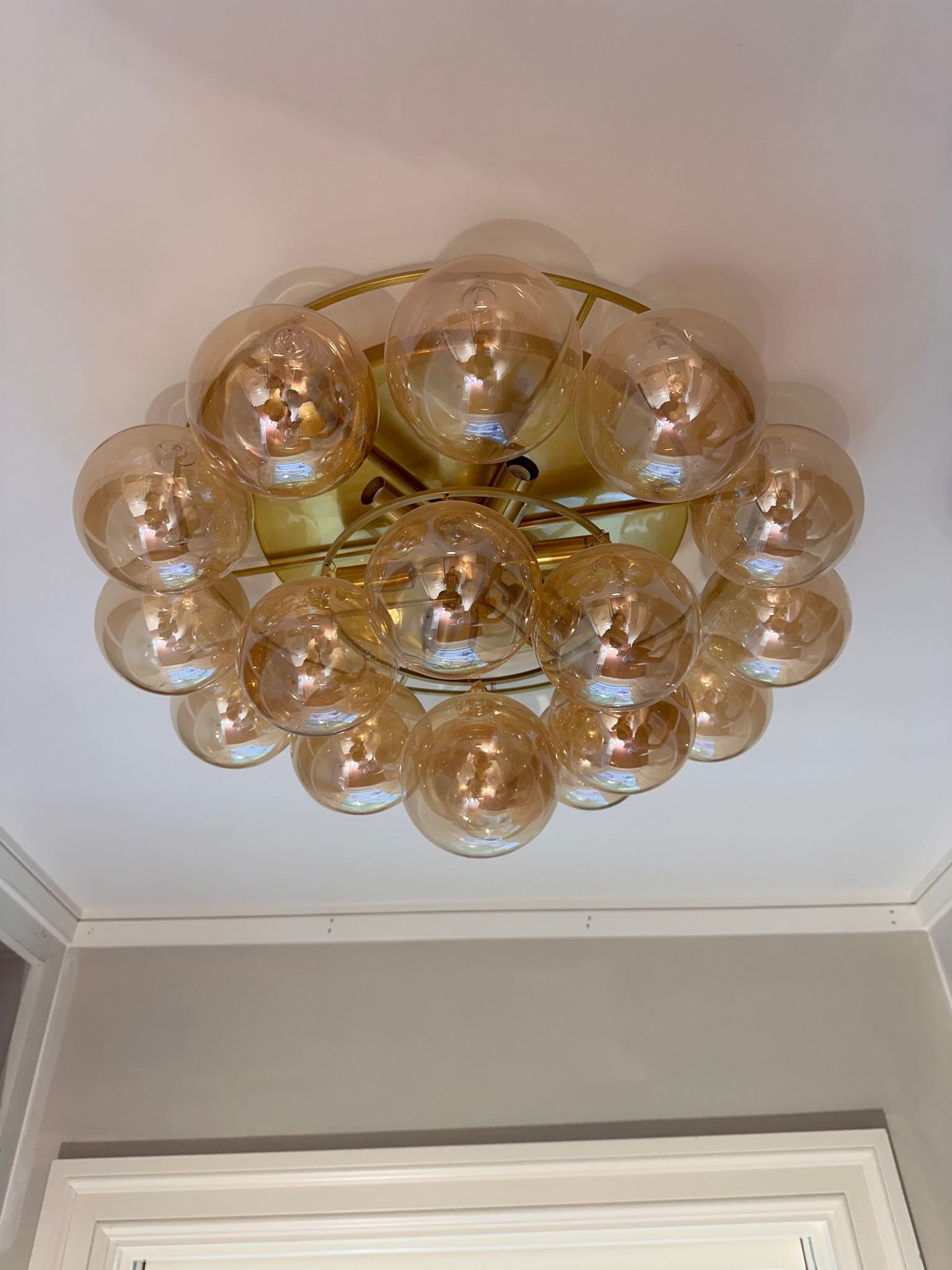 Gold bubble-glass ceiling light fixture on a white ceiling above a doorway