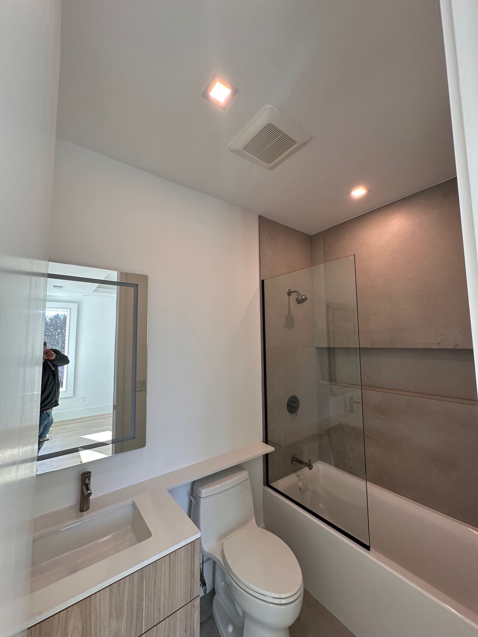Modern white bathroom with sink, toilet, mirror, bathtub, and glass shower enclosure