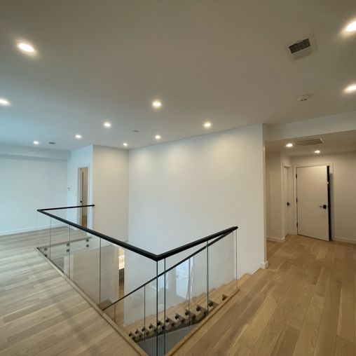 A hallway with stairs and a glass railing