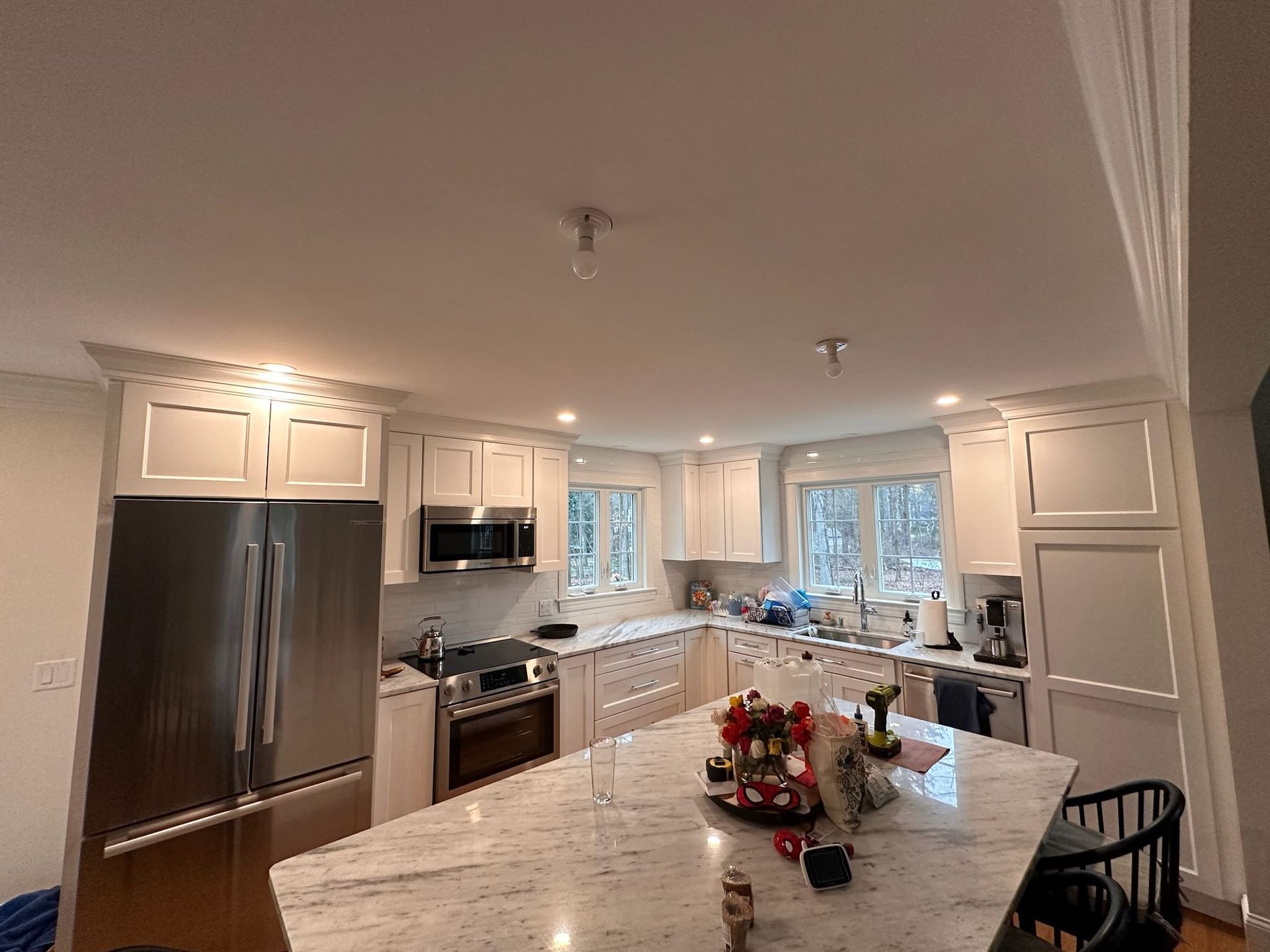 Bright modern kitchen with a large marble island, white cabinets, stainless appliances, and a decorated centerpiece