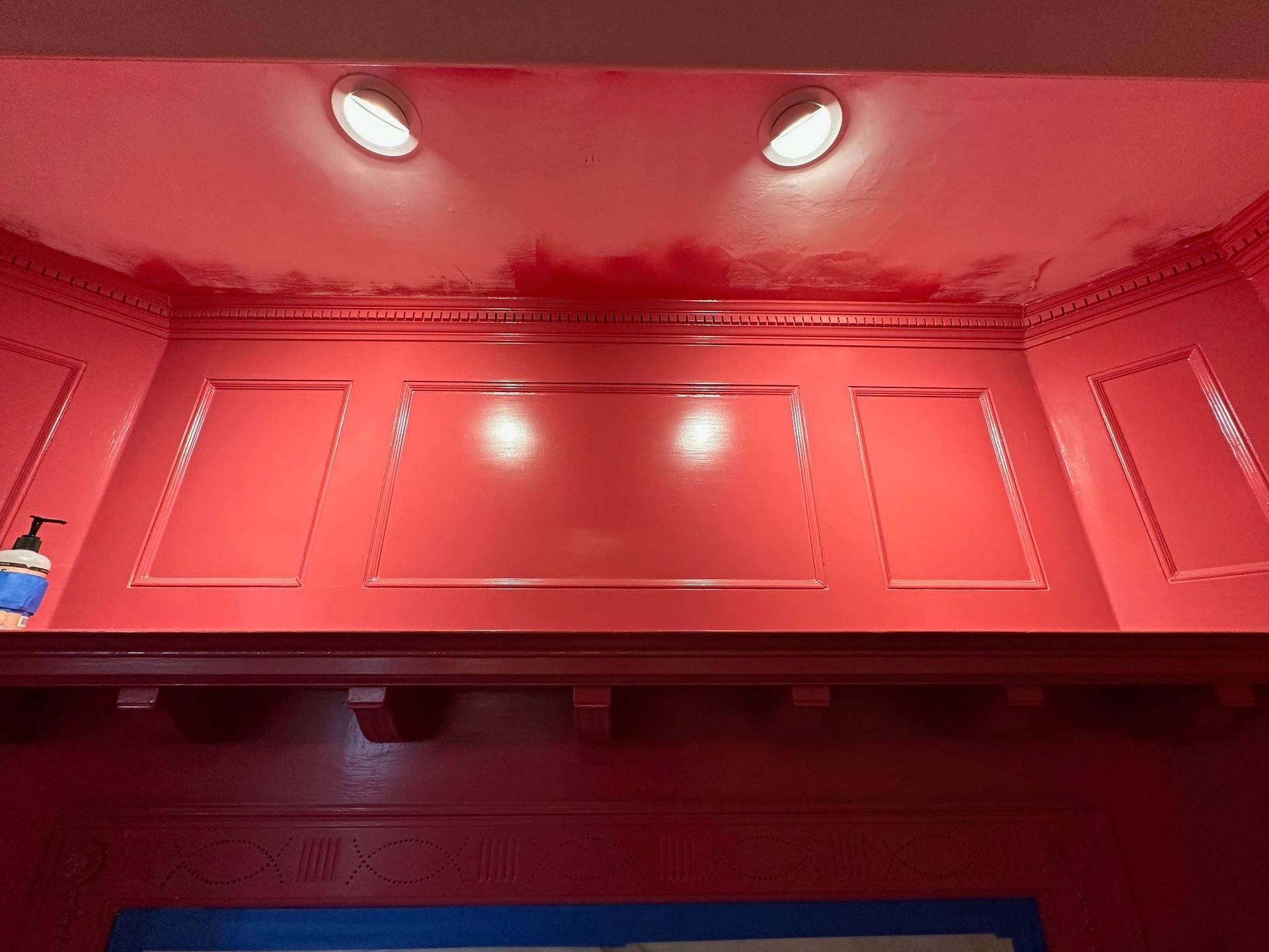Red-lit interior of a cabinet or display case with two ceiling spotlights and blue trim at the bottom