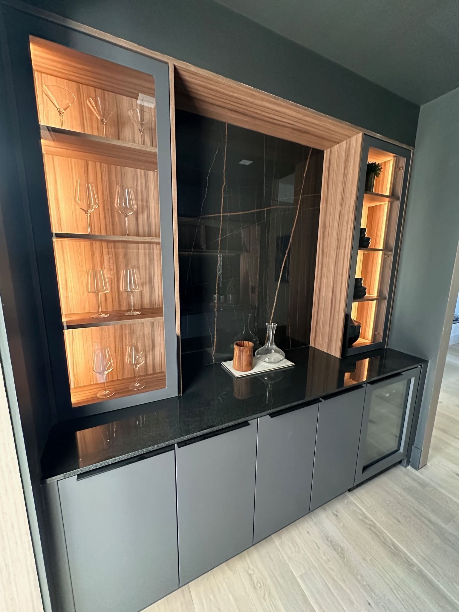 Built-in dark wood and gray entertainment wall unit with shelves, cabinets, and a TV niche