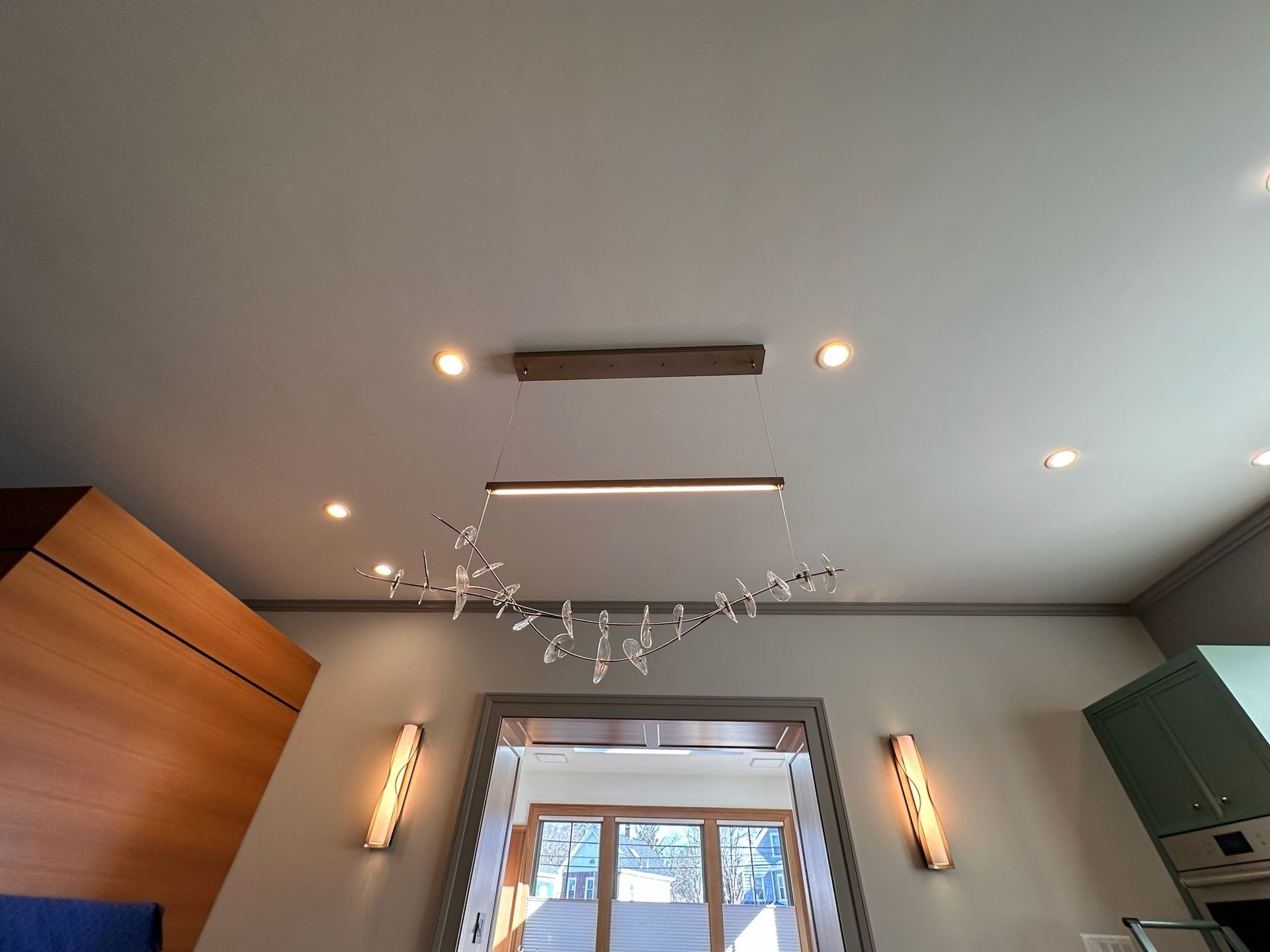 Modern room ceiling with recessed lights, hanging branch decor, and a window below