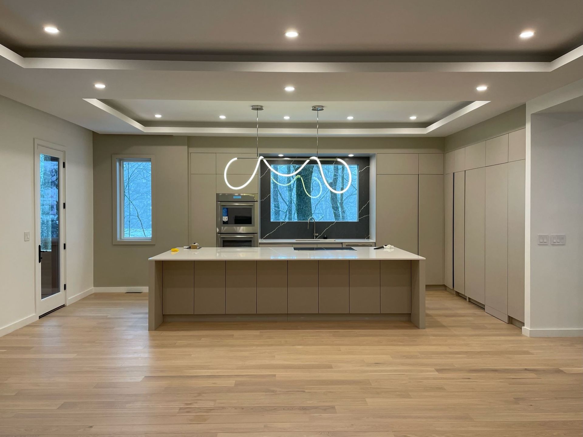 Modern kitchen with large island, light wood floors, recessed lighting, and pendant lights over the center island