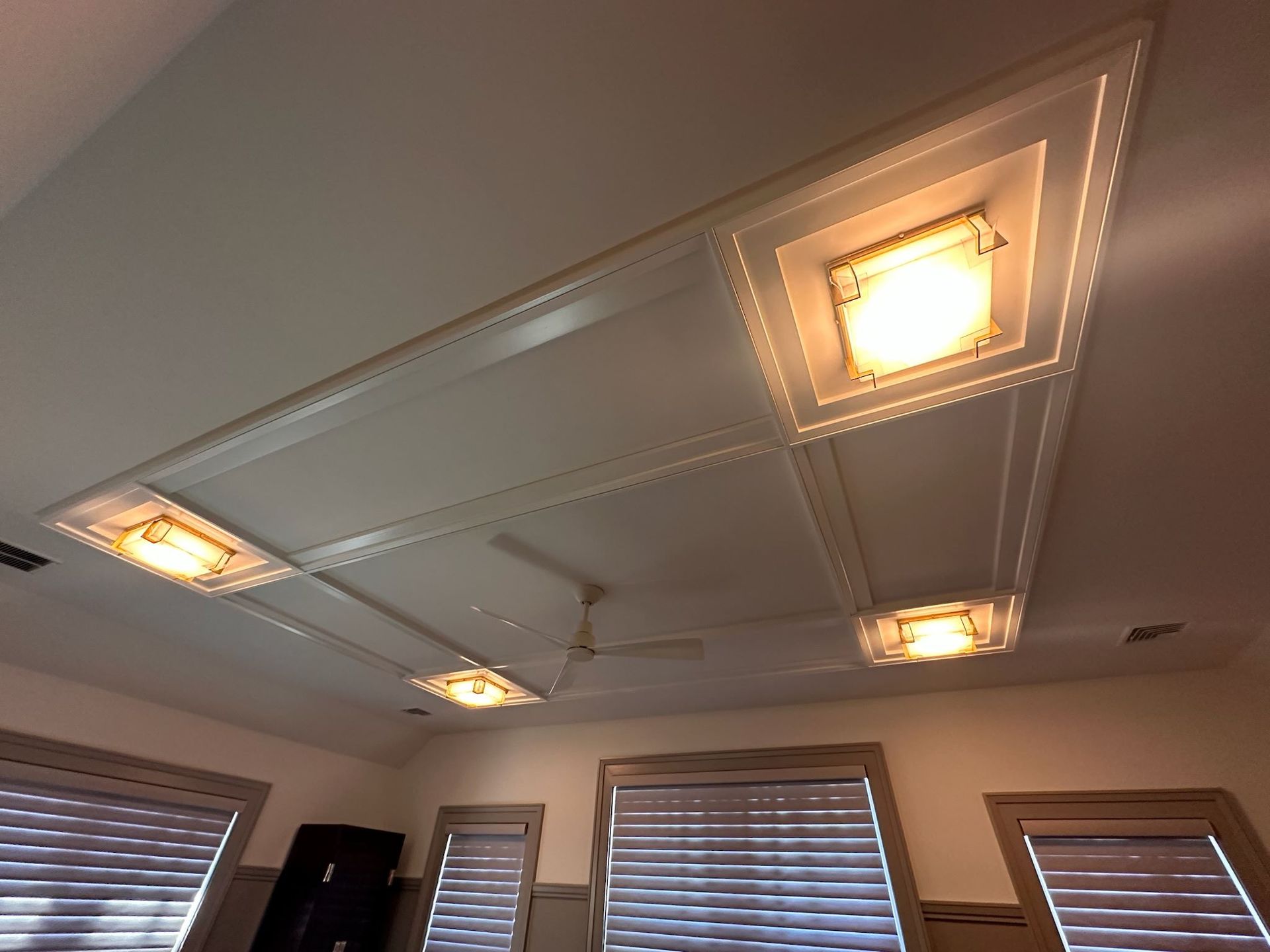 A room with a ceiling fan and a lot of windows