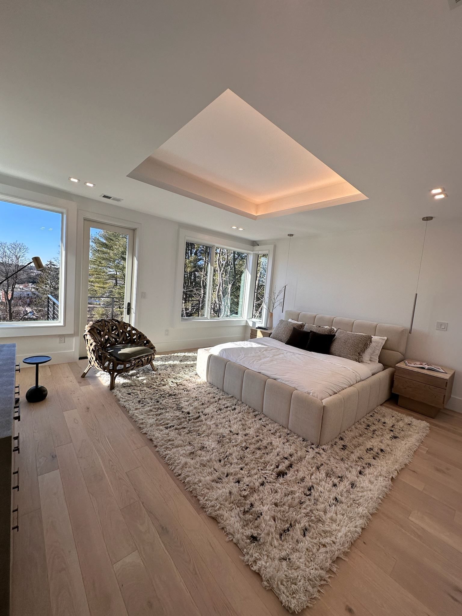 Bright modern bedroom with large windows, white bed, shag rug, and recessed ceiling lighting