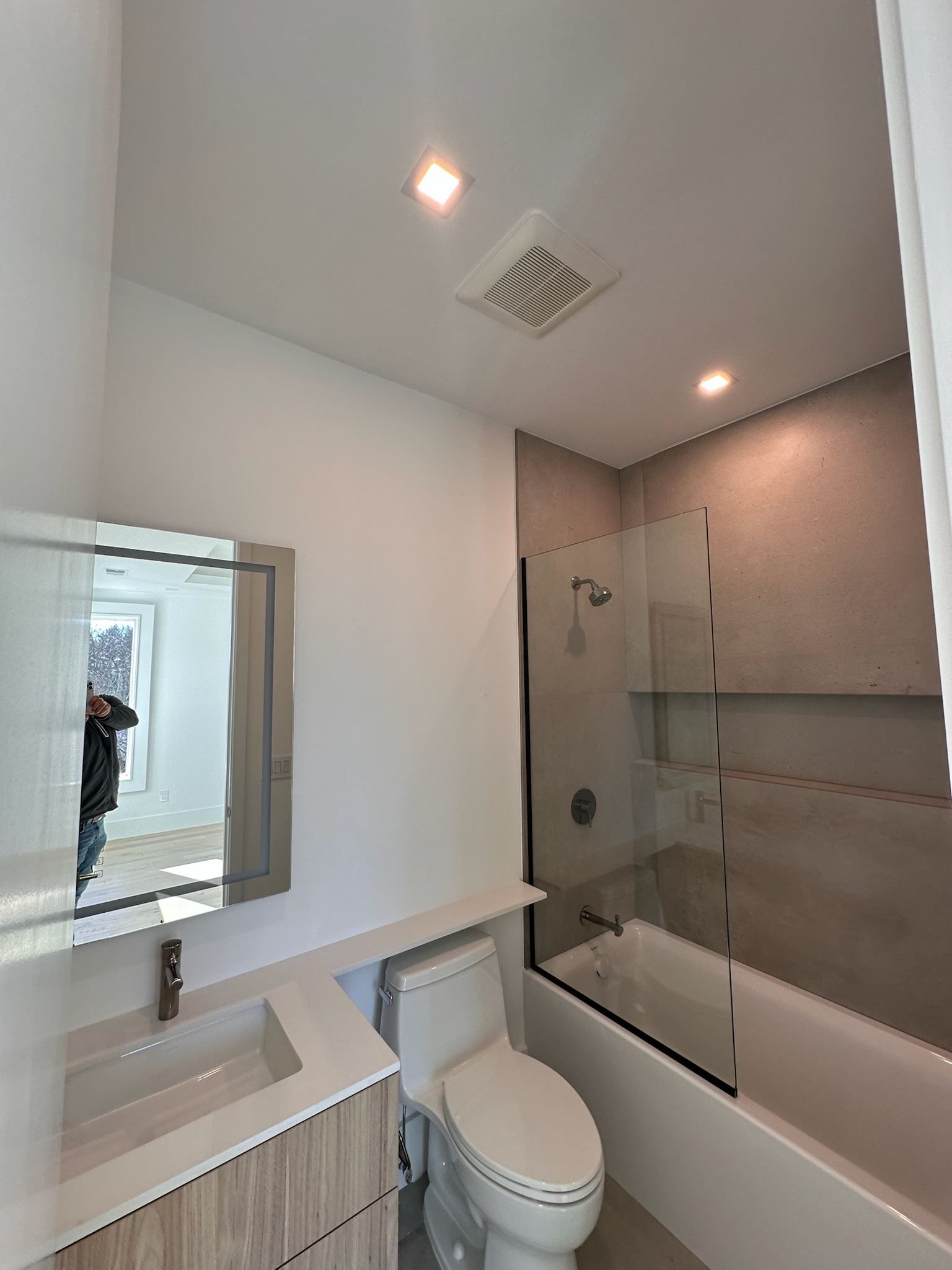 Modern white bathroom with vanity, toilet, bathtub, and glass shower enclosure