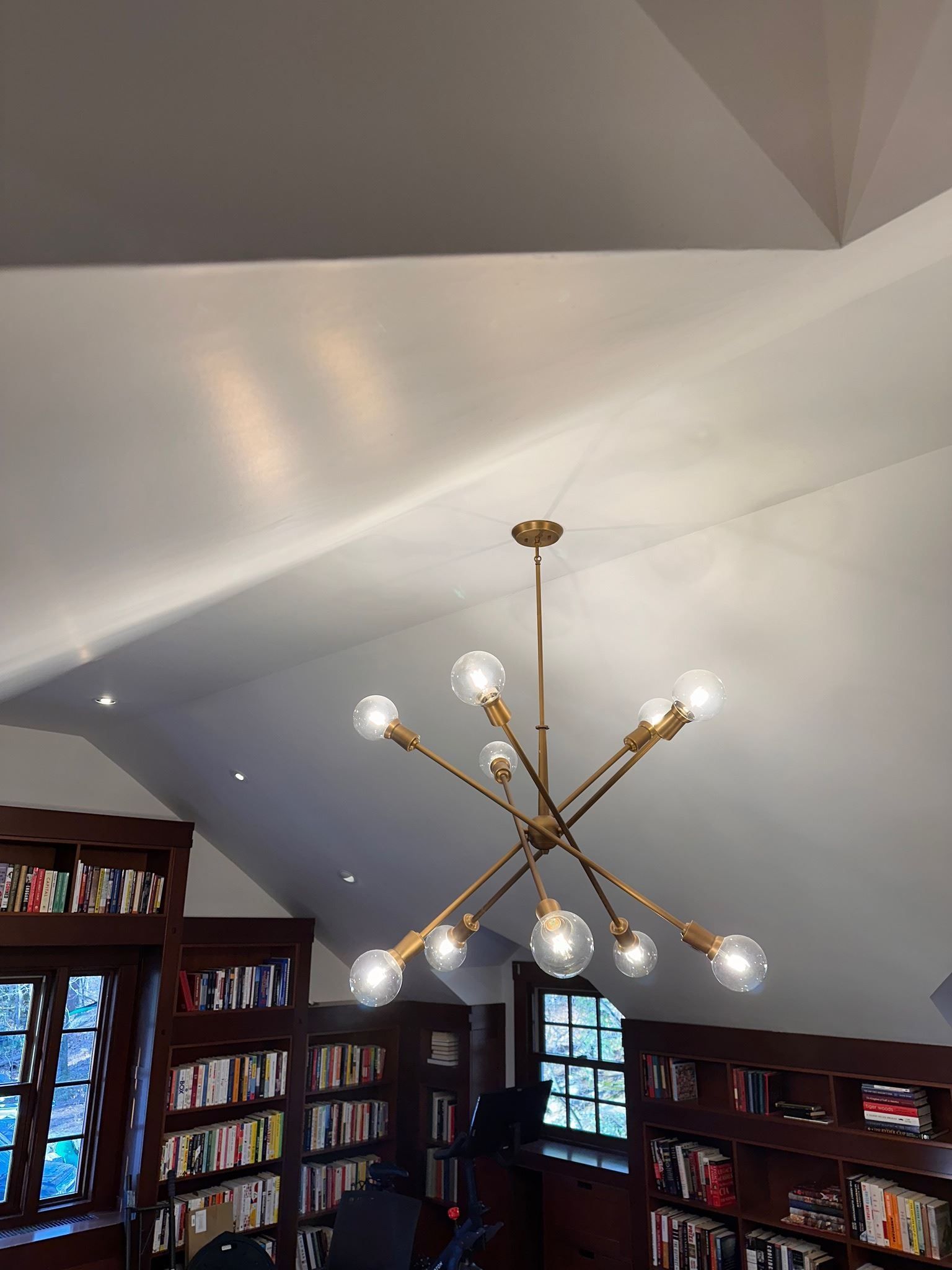 Library room with a gold chandelier and bookshelves lining the walls under a vaulted ceiling