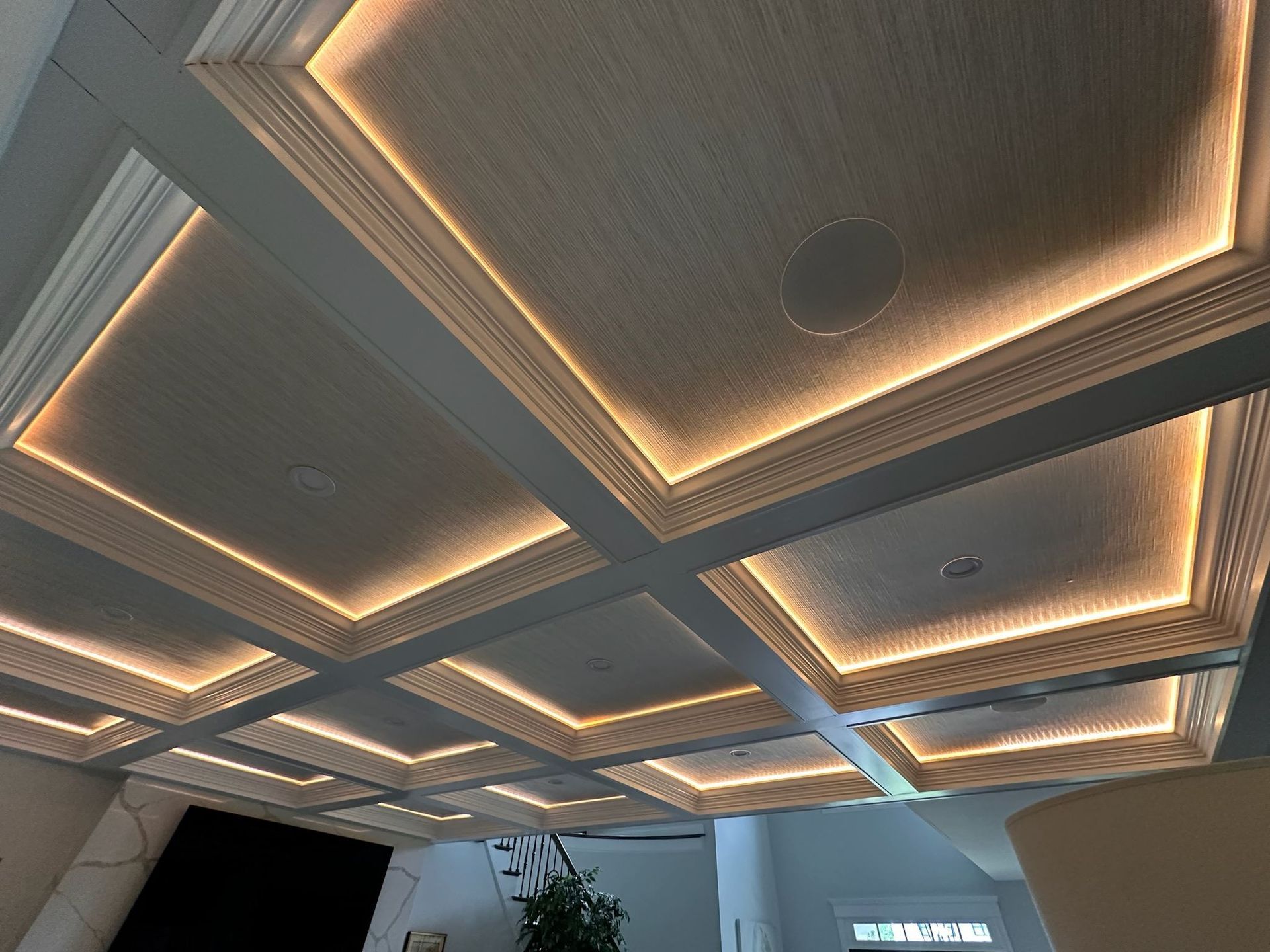 Modern lobby ceiling with geometric recessed panels and warm LED strip lighting