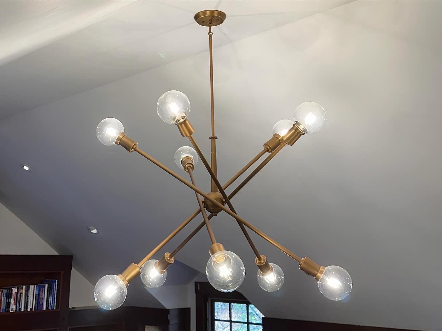 Modern brass chandelier with exposed bulbs hanging from a white ceiling