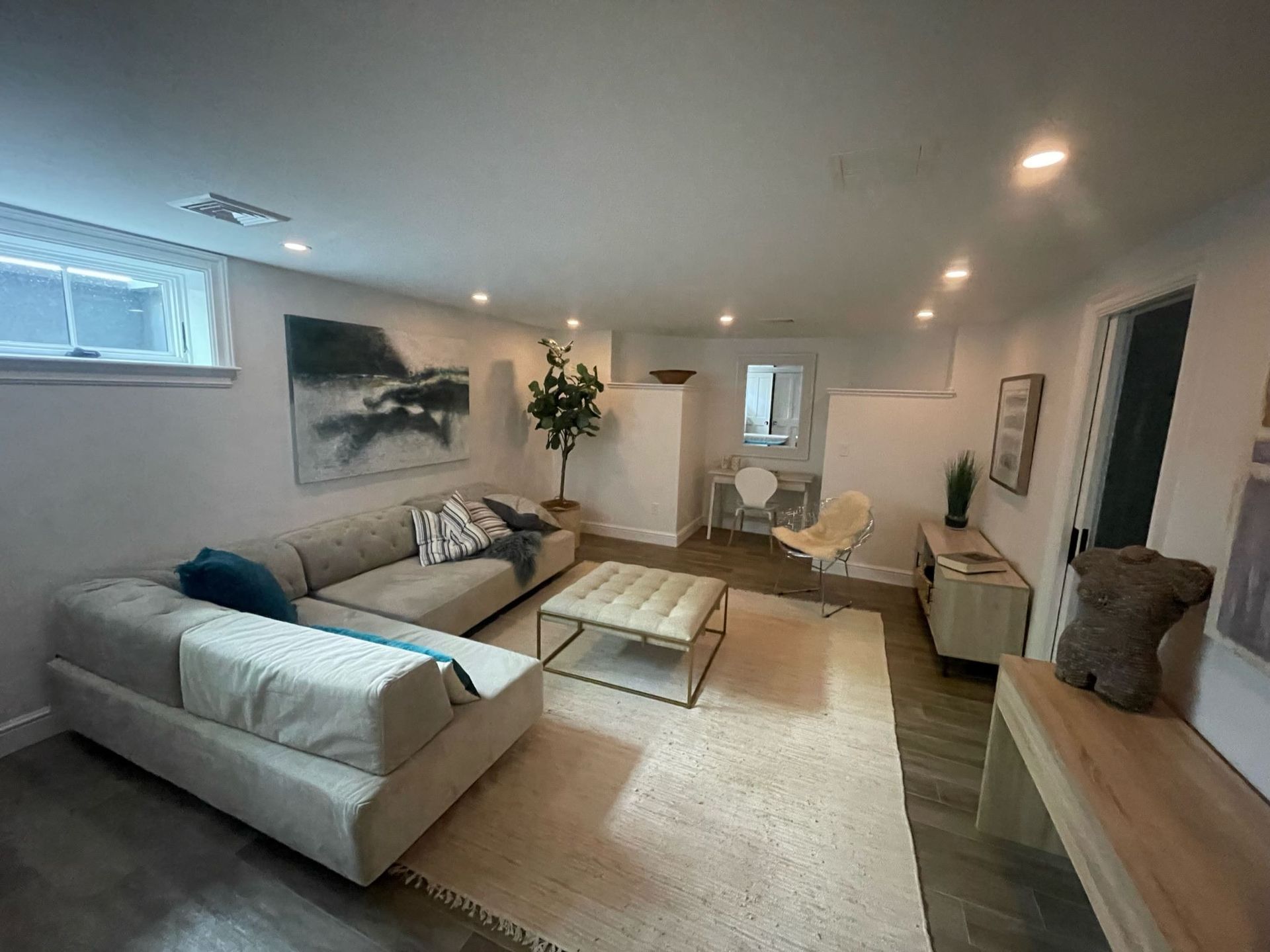 Bright modern living room with gray sofas, coffee table, rug, wall art, and warm ceiling lights