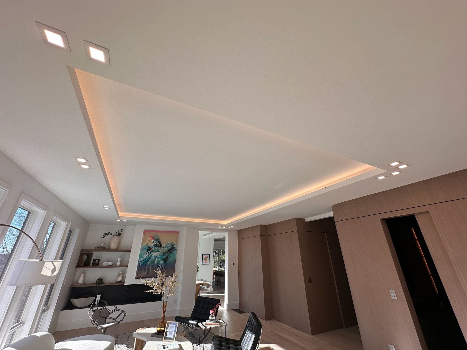 Modern living room with recessed ceiling lights, wall art, sofa, and open shelving.
