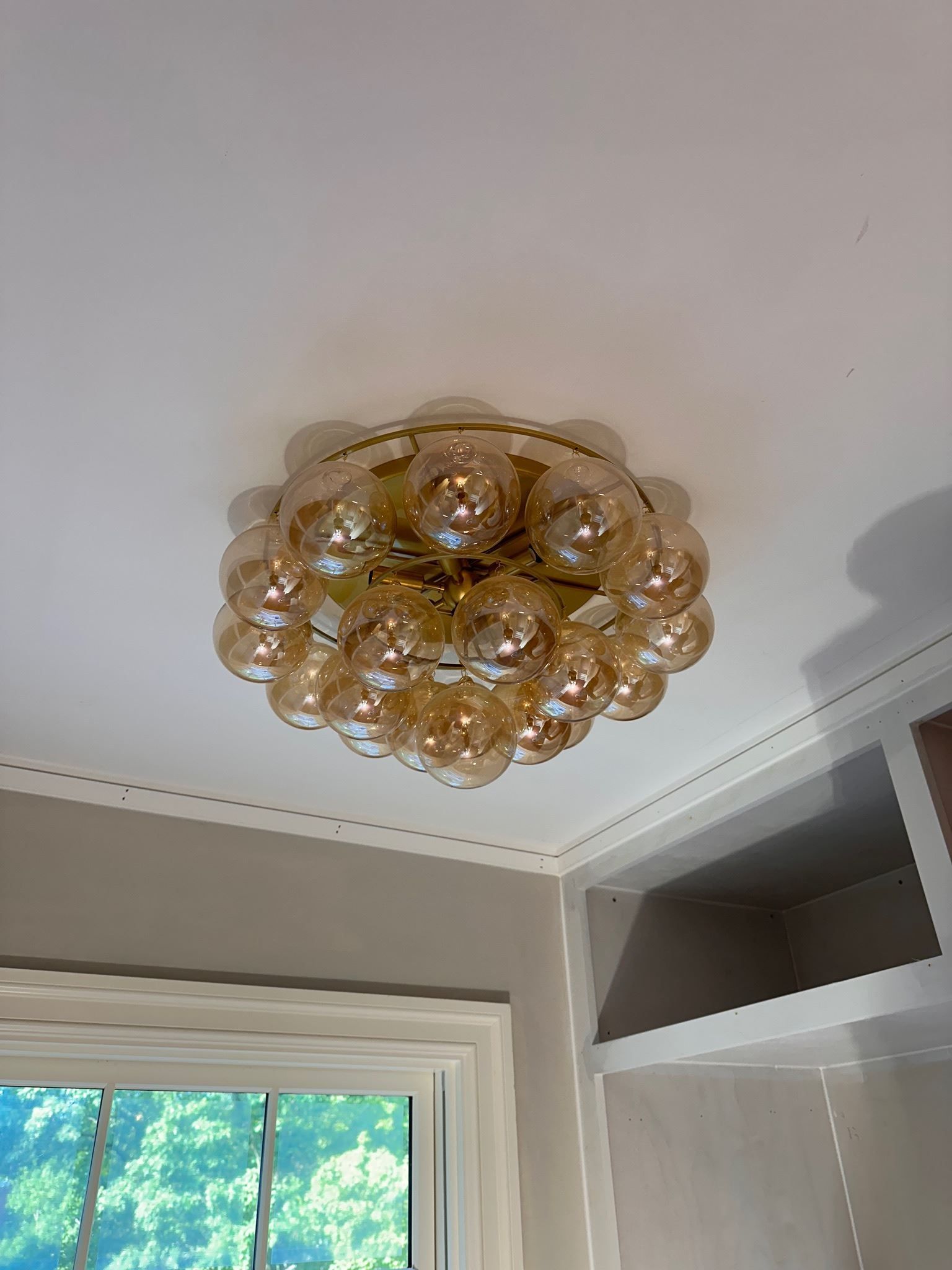 Gold glass ceiling light fixture in a room corner near a window